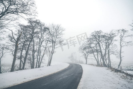 公路弯曲的道路在一个有雾的冬天风景与雪在路边