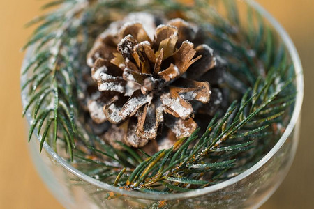 圣诞树枝摄影照片_圣诞概念-用甜点碗里的松果装饰冷杉树枝的特写。冷杉和球果圣诞装饰特写