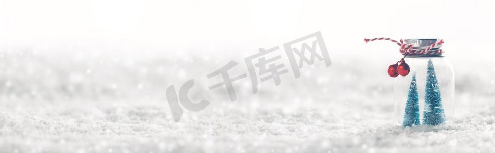 玻璃罐的圣诞装饰品与条纹丝带，铃铛和冷杉树里面在雪背景。圣诞装饰品在雪地上