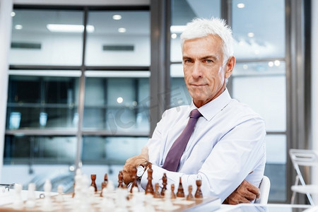 行动思考摄影照片_办公室里的生意人在下棋。思考下一步行动