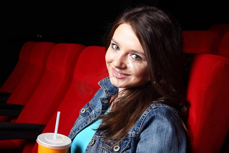 坐在车里看电影摄影照片_年轻女孩坐在电影院里看电影
