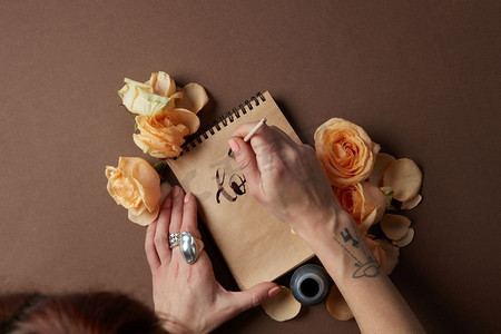 手写浪漫情书摄影照片_从上面的妇女用画笔在纸上写字的视图。手写情书