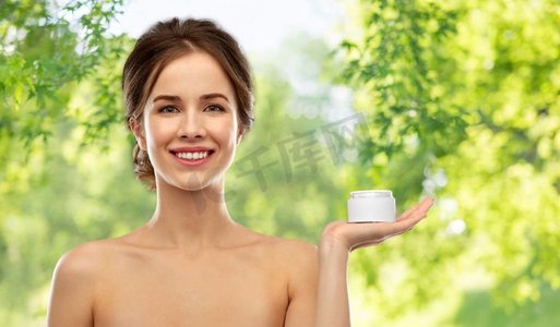 美容、化妆品和护肤概念—拿着在绿色自然背景的奶油罐的愉快的年轻女子快乐的年轻女子拿着一罐奶油