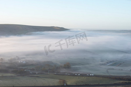 冬天日出时分美丽的雾蒙蒙的英国乡村风光，层层穿过田野
