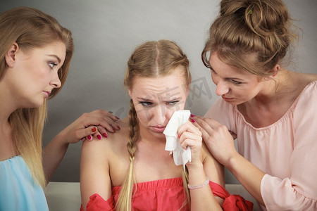 女性安慰她的女性朋友，当她感冒的时候，流鼻涕的人朝纸巾上流鼻涕。朋友在发烧期间帮助女人。