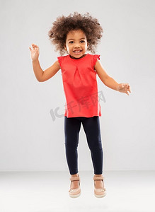 童年和人概念—快乐的小非洲裔美国人女孩跳跃或飞行在灰色背景快乐的小非洲裔美国人女孩跳跃