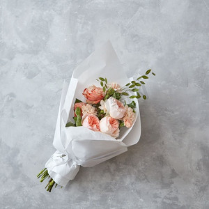 结婚花束桃玫瑰与白纸在灰色石头背景。美丽的桃玫瑰