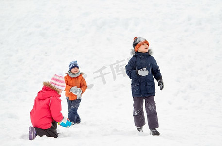 小孩子摄影照片_童年，休闲和季节概念—一群穿着冬装的快乐的小孩子在户外玩耍。快乐的小孩子在冬天户外玩耍