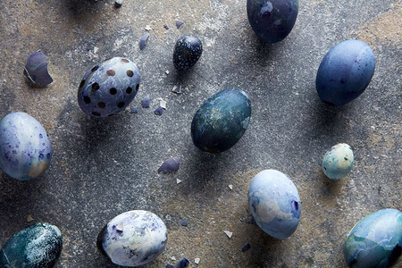 以蛋壳和蓝色彩蛋为黑色背景作为复活节背景。蛋壳和蓝色的鸡蛋