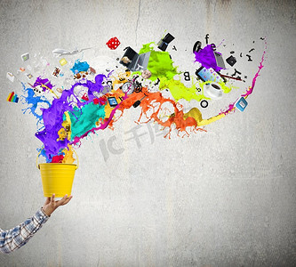 创意概念。手从彩色水桶中溅起彩色油漆的特写