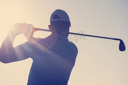 高尔夫上杆摄影照片_在阳光灿烂的早晨，高尔夫球手在球场上用球杆击球。高尔夫球手击球