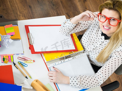 快乐的女商人感觉精力充沛坐在办公桌前工作,满满的活页夹里的文件.