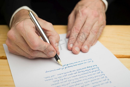 一个商人用钢笔在一张白纸上写字，放在一张树木繁茂的甲板上