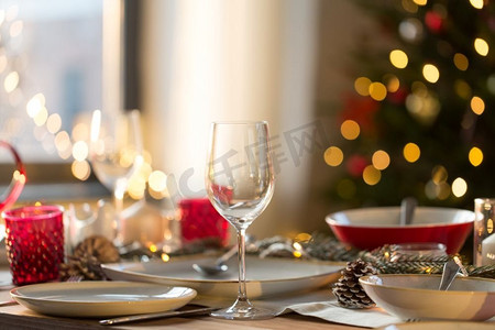气球雨布置摄影照片_圣诞节，节日及餐桌布置概念—家庭节日晚餐的酒杯及餐具。圣诞晚餐的餐桌布置
