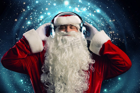 音乐圣诞老人摄影照片_新年晚会。圣诞老人戴着耳机享受音乐