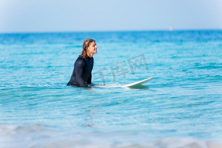 一名年轻的冲浪者在海滩上挥舞着冲浪板。准备好掀起波澜