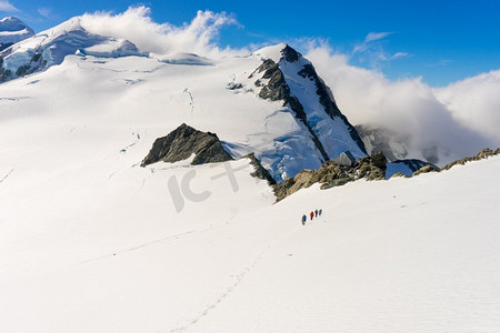 登山徒步的人摄影照片_新西兰。在新西兰山区的雪地中行走的一群人