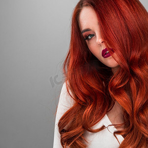 红发摄影照片_女人的美丽肖像。艳丽性感迷人的红发性感模特，一头闪亮的卷发。美丽的红发模特女孩