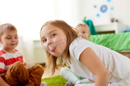 童年、休闲和面部表情的概念--女孩在家中秀舌头。女孩在家里说三道四