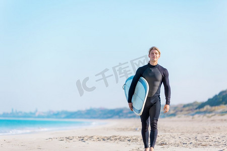 一名年轻的冲浪者在海滩上挥舞着冲浪板。准备好掀起波澜