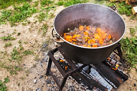 美味的匈牙利炖牛肉汤配上辣椒粉和牛肉。自然界中的传统烹饪。火盆着火