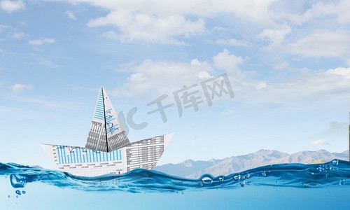 漂浮在水面上摄影照片_金融安全的概念。漂浮在水面上的图形和图表的纸船