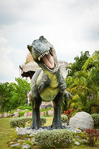 孔敬，泰国2018年5月13日：恐龙公园/不同种类的恐龙霸王龙雕像T rex在棕榈树花园