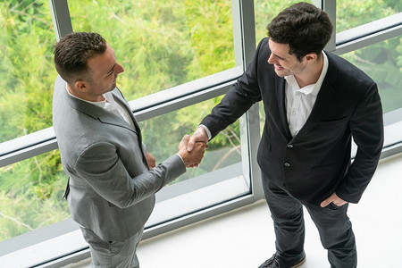 商人握手与另一个商人伙伴在现代工作场所办公室。人的企业商业交易概念。