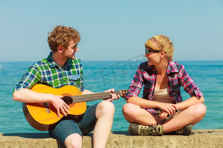 一对在海边约会的情侣在户外为女友弹吉他
