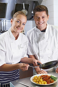 厨师在餐厅厨房指导女学员的画像