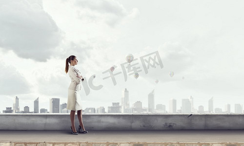 新的一天开始营业了。年轻优雅的女商人站在屋顶上看着城市