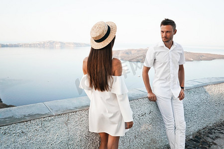 白色欧洲小镇幸福的年轻夫妇的户外生活照片。走在圣托里尼岛上