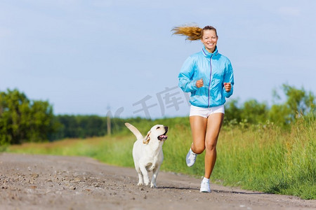 在户外跑步。年轻健康的女孩带着她的狗在户外跑步