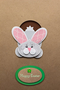 有创意的复活节概念照片，一只兔子在棕色背景下用纸做的洞里。