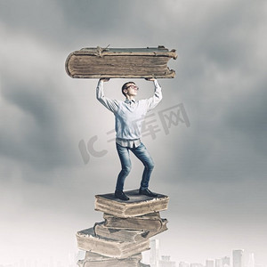 知识和教育。一个年轻人头上举着一本巨大的书