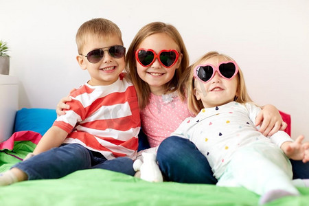 夏天，情人节和童年的概念-戴着心形太阳镜的小孩子们在家里快乐。家里戴着墨镜的快乐小朋友