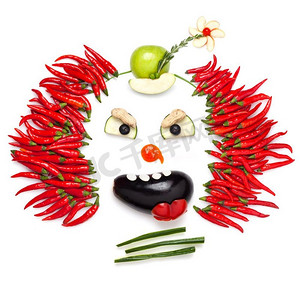 一个创意食品概念，展示了一个令人毛骨悚然的万圣节小丑，在辣椒和其他蔬菜的帮助下。