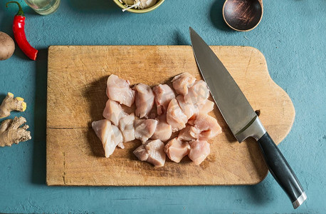 切鸡摄影照片_切菜板上的鸡块，餐桌上有刀，俯瞰。烹饪准备