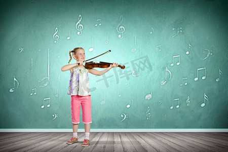 小提琴中提琴摄影照片_拉小提琴的女孩。在绿色背景下拉小提琴的可爱女孩形象