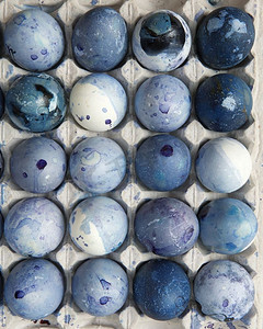 蓝色彩绘复活节彩蛋躺在白色托盘作为背景，平躺。托盘里有漆蓝色的鸡蛋