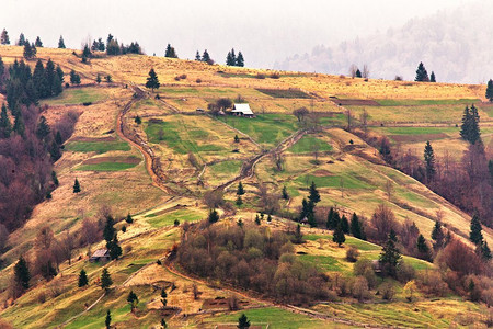 山坡上的山村。绿色的山丘在山谷。春天的风景。农业领域的丘陵