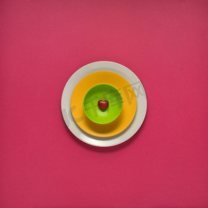瓷盘子摄影照片_粉色背景上彩绘盘子的创意概念照片。
