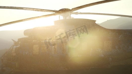 武器军队摄影照片_日落时分，一架破旧的军用直升机在沙漠中