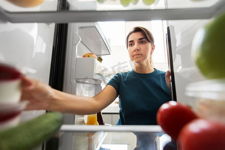 健康饮食，食物和饮食概念—妇女从冰箱在家庭厨房。女人从家里的冰箱里拿食物