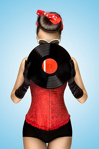 一张复古美女的复古照片，穿着红色性感紧身胸衣，躲在蓝色背景的复古黑胶后面。