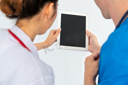 女医生在与医院的另一名医生讨论时使用平板电脑。医疗保健人员和医生服务。