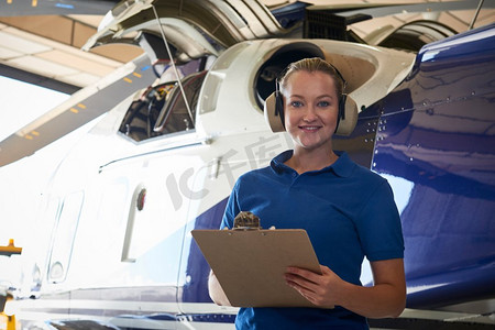 女航空工程师在机库用剪贴板对直升机进行检查
