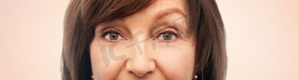 美貌、视野和老人观念--米色背景下的老年女性的半脸。米色背景以上的资深女性半张脸