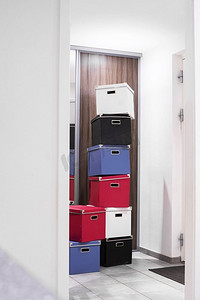 堆叠的盒子在各种颜色在一个明亮的房间在门口