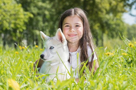 哈士奇小狗狗摄影照片_小女孩与哈士奇小狗。微笑的小女孩与哈士奇小狗在公园